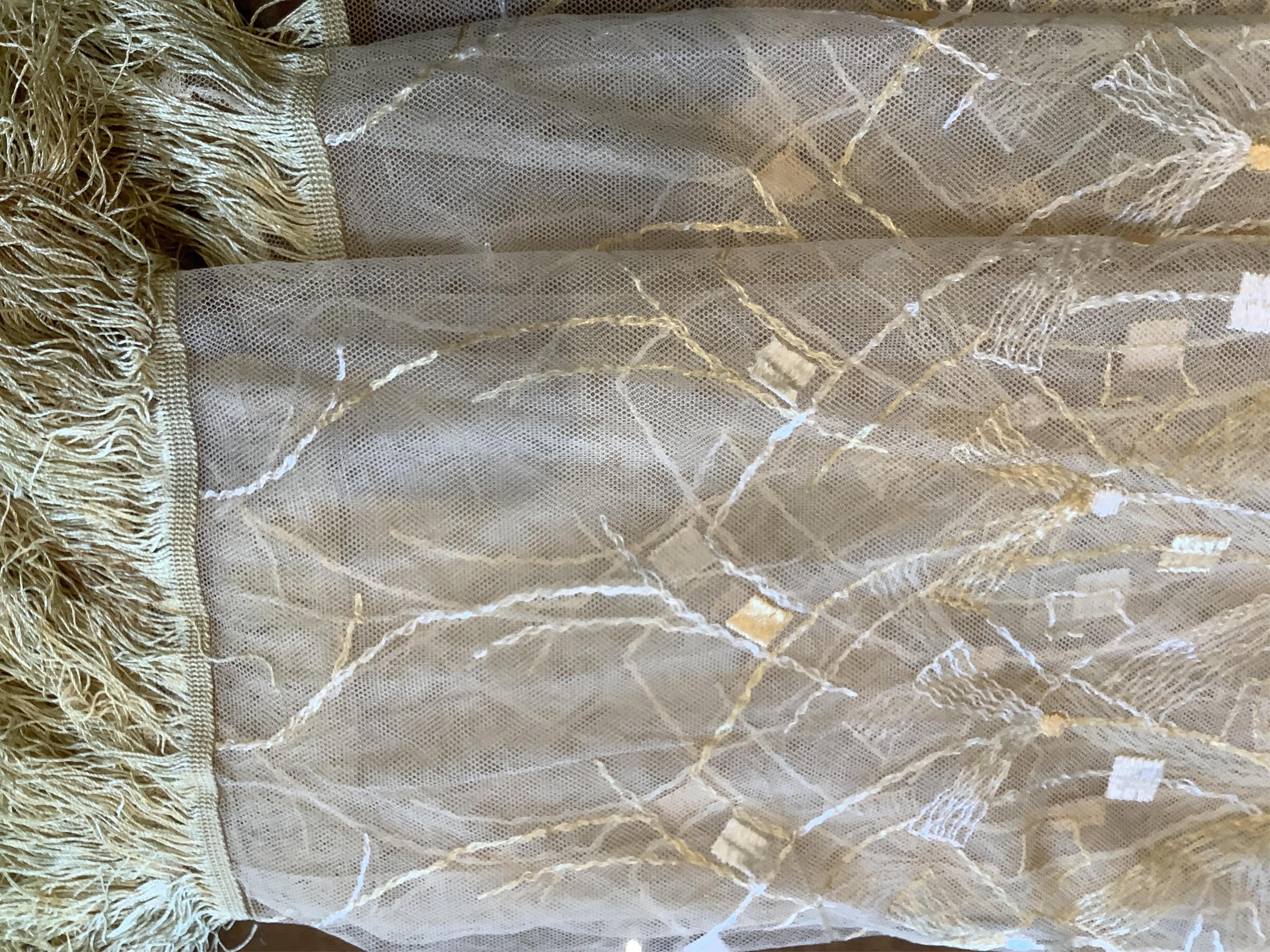 A French Art Deco wide silk yellow and cream embroidered net curtain, bordered at the bottom with yellow silk fringing. Approximately 560cm wide x 170cm long (not including fringing)., Condition - the curtain may need re